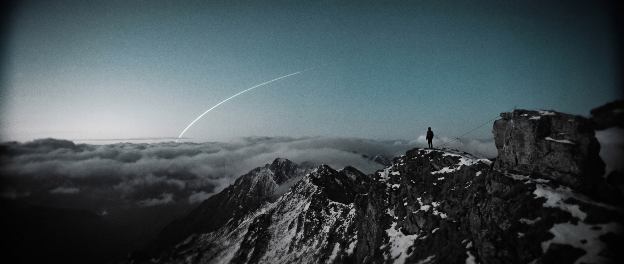 A lone figure on a mountain ridge at blue hour
