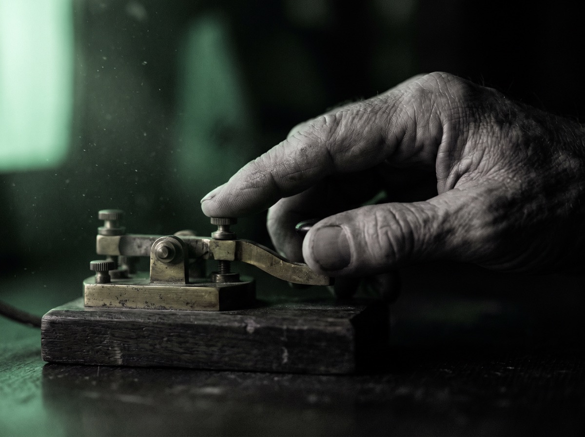 A hand on a Morse key in a dark room